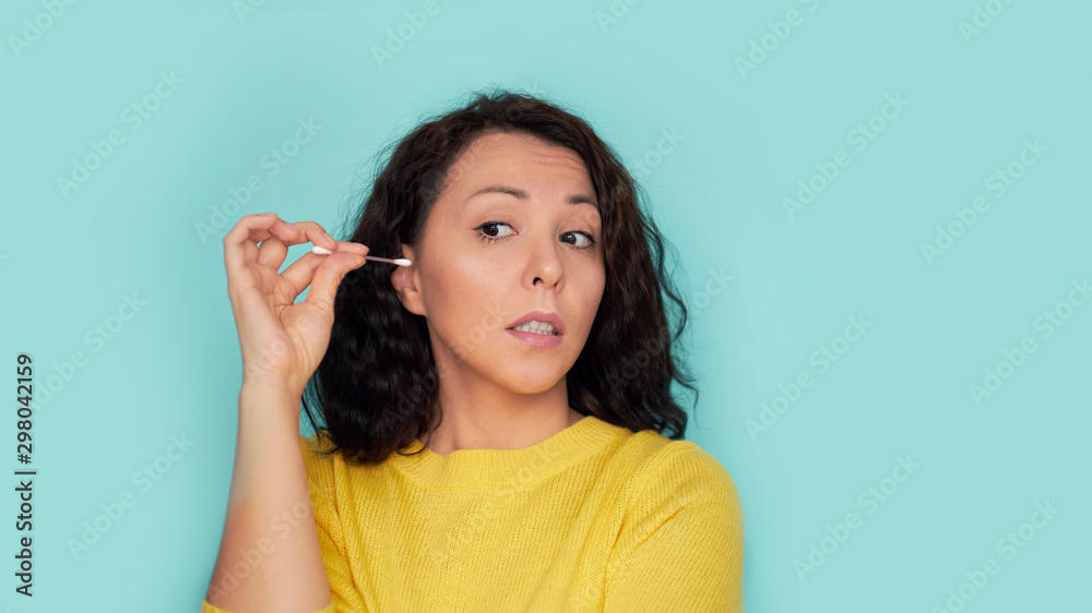ear care. woman cleans her ear with a cotton swab. cotton swab injury ear care. woman cleans her ear with a cotton swab. cotton swab injury