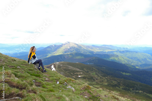 Young happy female tourist wearing yellow jacket sitting in Appenine mountains. photo