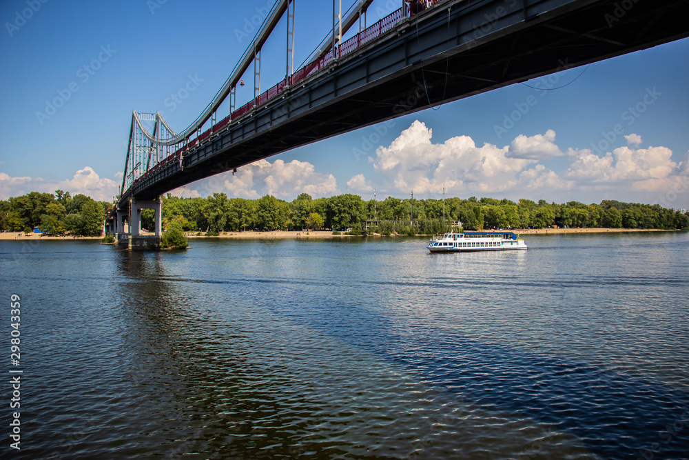 Naklejka premium Tour of Kiev in the center of Europe. View of the Dnieper, Trukhanov island and a foot bridge. Park fountain and sunset on the horizon..