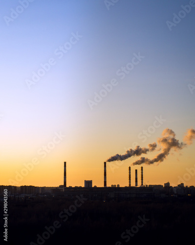 Colorful Magic Sunset. Dark smoke coming from the thermal power plant pipe. vertical photo