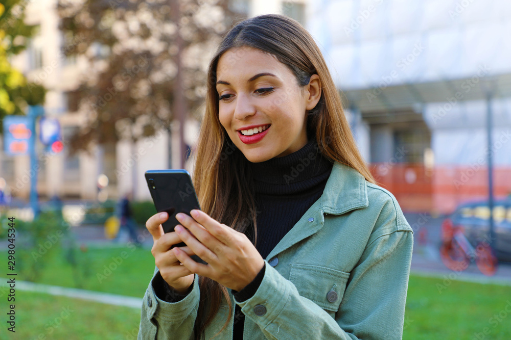 Young woman with smart phone chatting outdoor in fall or winter season.
