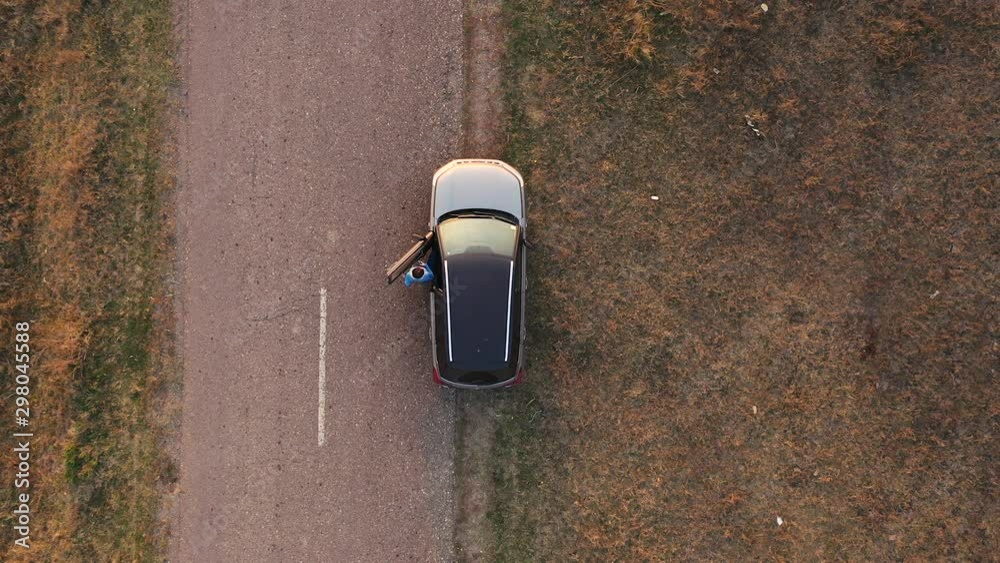 Aerial view woman entering car and driving away