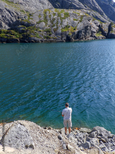 landscape with rocks  clear and blue fjord water  mountains in the background