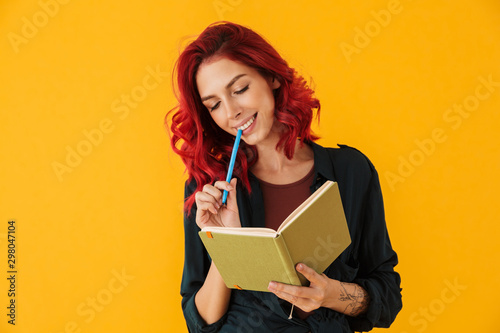 Image of attractive smiling woman holding exercise book and pan