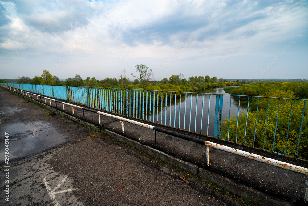 Old bridge, river and trees on calm day. Natural landscape