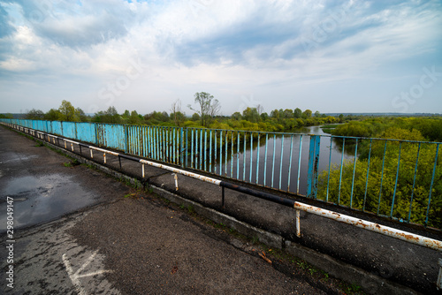 Old bridge  river and trees on calm day. Natural landscape