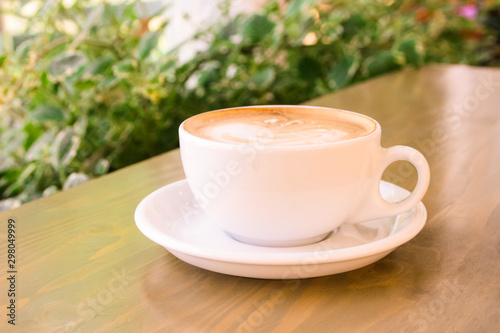 white cup with coffee on the table, in the morning, in a cafe on a bright veranda, close-up, selective focus