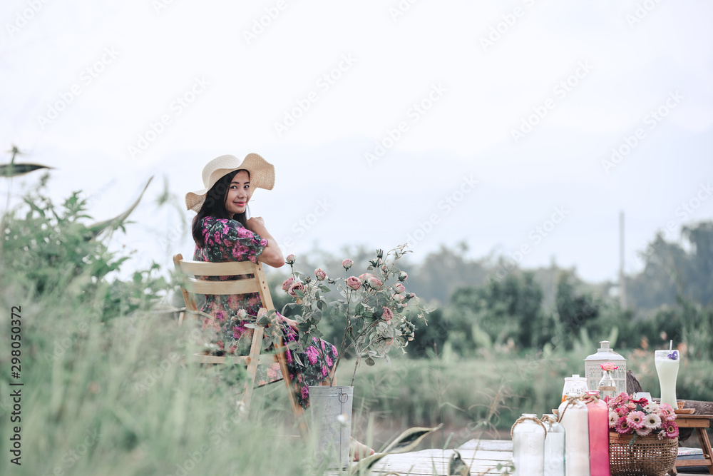Obraz premium The girl wearing a red floral dress sitting on the waterfront with green nature views