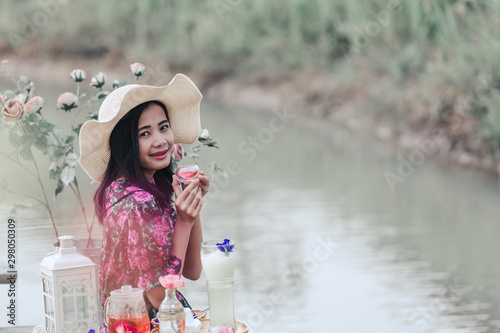 The girl in red floral dress that sits tea at the waterfront. © artit