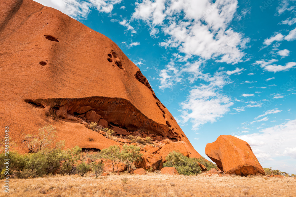 Woman walks on red sand dune in Australia, fiery red sand eroded from huge rock formation and a sanctuary for the Aboriginals