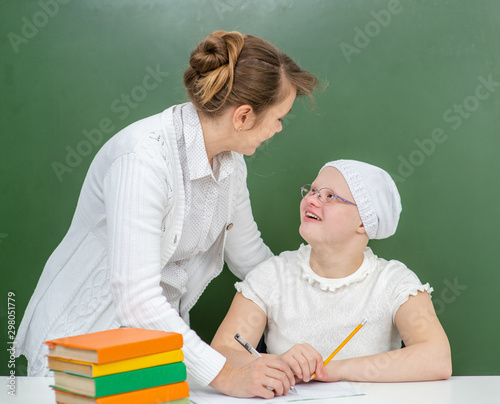 Teacher helps young girl with Down Syndrome at school photo