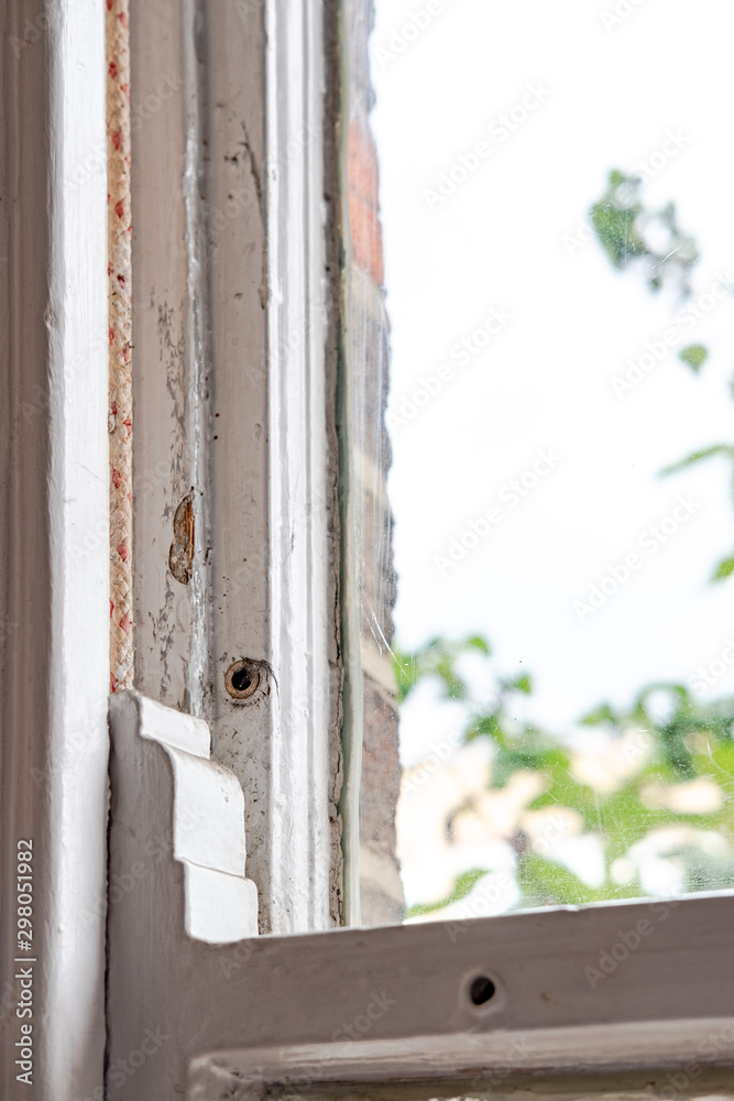 Shallow focus, isolated image of an old style sash window shown in the closed position. Part of the sash running cord can be seen on the left, within a wooden grove. Shallow focus, isolated image of an old style sash window shown in the closed position. Part of the sash running cord can be seen on the left, within a wooden grove.