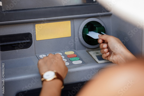 Close-up of woman entering pin while using ATM machine.