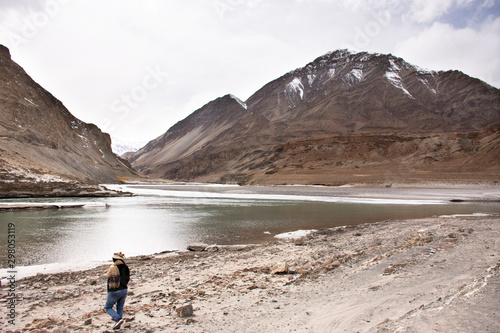 Travelers thai woman travel visit and posing portrait for take photo at view point of Confluence of the Indus and Zanskar Rivers while winter season at Leh Ladakh in Jammu and Kashmir, India