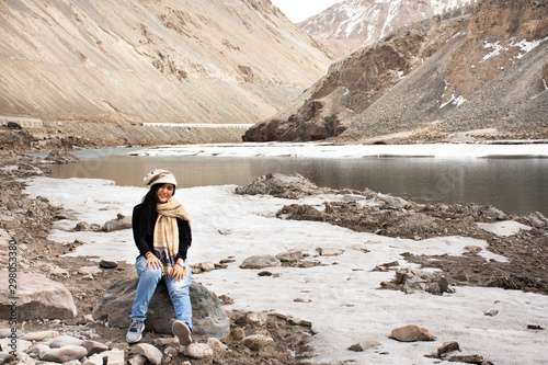 Travelers thai woman travel visit and posing portrait for take photo at view point of Confluence of the Indus and Zanskar Rivers while winter season at Leh Ladakh in Jammu and Kashmir, India