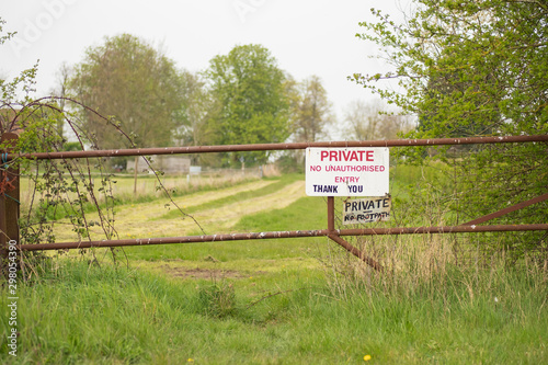 hallow focus of a makeshift Private Property sign seen at the entrance to private pasture. Secured by a metal gate to prevent trespassers during darkness. photo