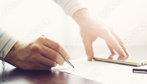 Business meeting. A man signs a contract. Male hand with pen makes notes in the office.