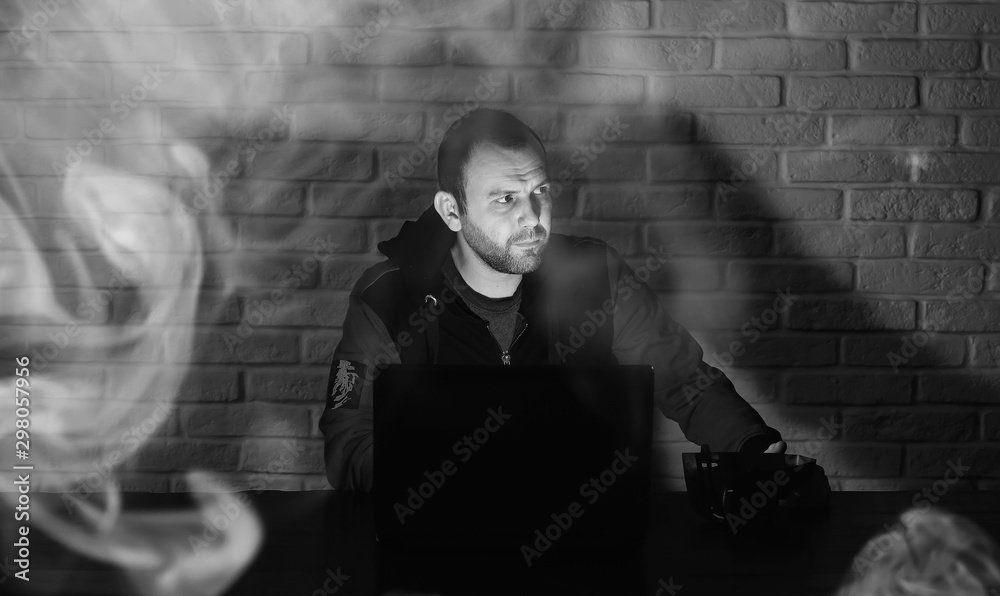 Fototapeta premium Hacker in black mask and hood at the table