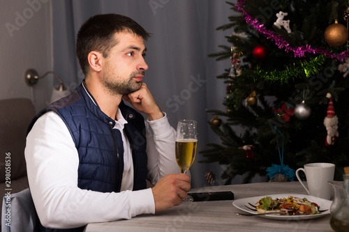 Young man celebrating New Year  having dinner  watching tv