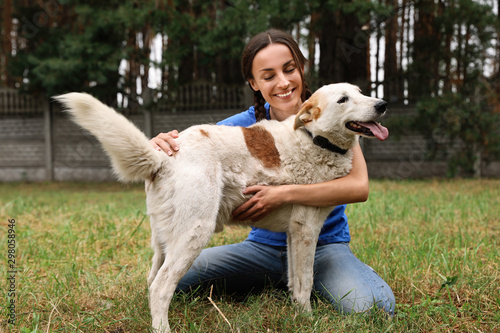 Fototapeta Female volunteer with homeless dog at animal shelter outdoors
