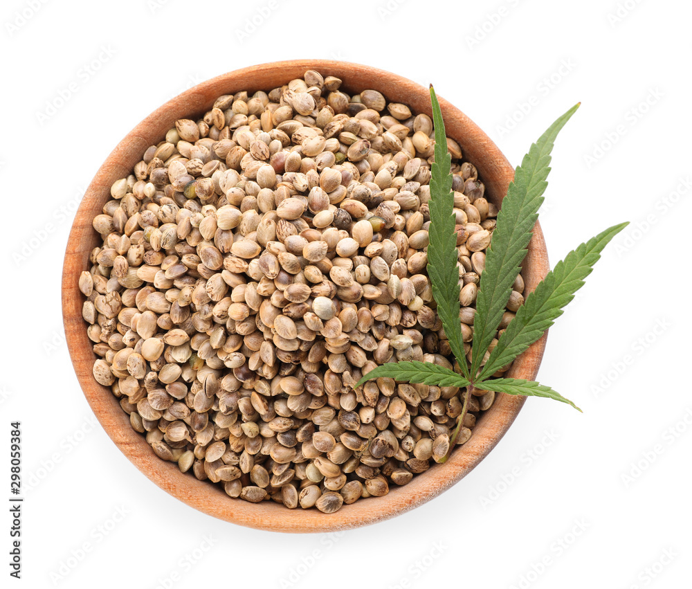 Fototapeta premium Wooden bowl of hemp seeds and leaf on white background, top view