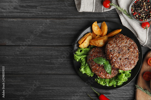 Flat lay composition with grilled meat cutlets for burger on black wooden table. Space for text