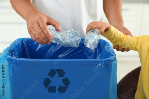 Father and son sorting garbage in kitchen, closeup. Recycling concept