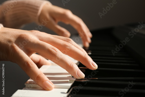 Young woman playing piano against grey background, closeup