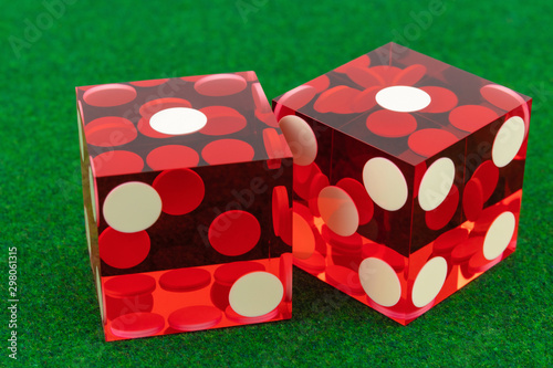 Two red glass professional dice on a green fleecy cloth. One and one macro photography, concept of excitement and game.