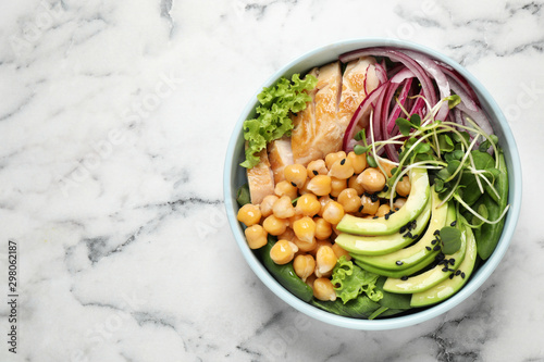 Delicious avocado salad with chickpea on white marble table, top view. Space for text