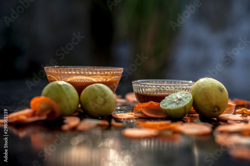 Carrot face mask on a black wooden surface consisting of some freshly sliced carrots paste, lemon juice, and honey well mixed in a glass bowl for the treatment of acne. photo