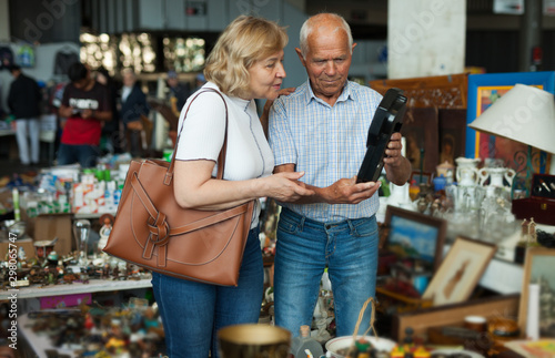 Elderly couple in flea market chooses antique items