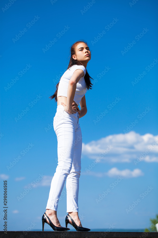 Beautiful brunette woman posing against blue sky bright sunny weather Beautiful brunette woman posing against blue sky bright sunny weather