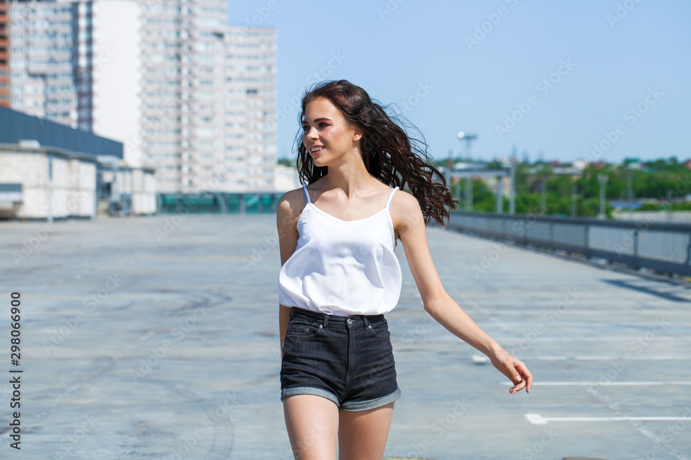Pretty young brunette model in white summer blouse and jeans, summer street outdoors Pretty young brunette model in white summer blouse and jeans, summer street outdoors