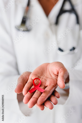 Woman african doctor holding red ribbon on her palms. AIDS awareness symbol