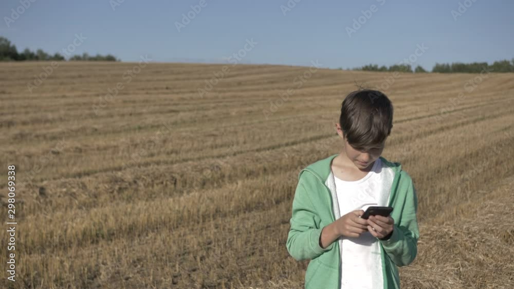 boy in the field uses the phone, chat with friends boy in the field uses the phone, chat with friends
