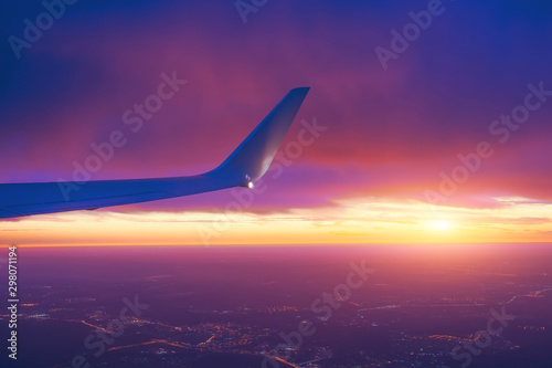Sunset sky from an airplane side wing view of the horizon and city lights.