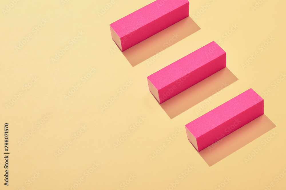 Three pink nail buffer block on yellow background Three pink nail buffer block on yellow background