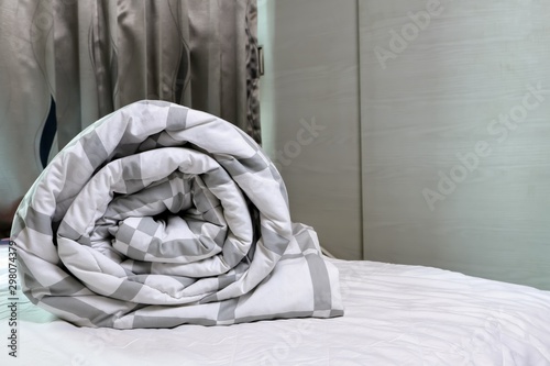 Blanket roll on the white spread of bed in bedroom, prepared to wash. © agencies