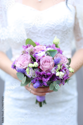 Closeup vioelt bouquet of flowers in fiancee hands. photo