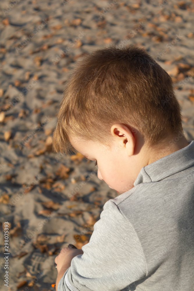 Little kid boy dreaming, pensive, on the beach near the water Little kid boy dreaming, pensive, on the beach near the water