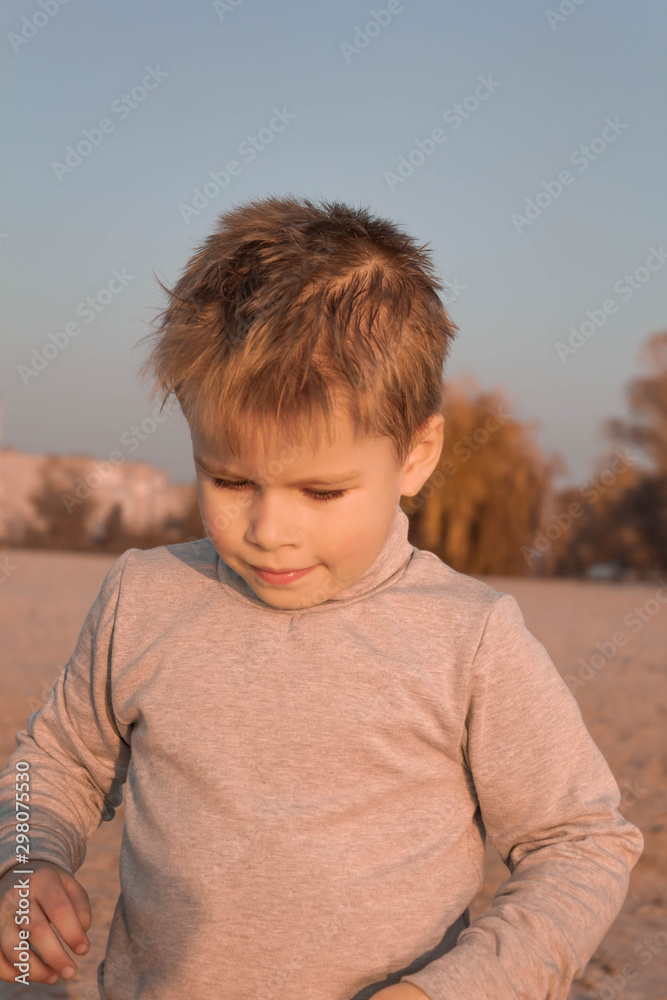 Little kid boy dreaming, pensive, on the beach near the water Little kid boy dreaming, pensive, on the beach near the water
