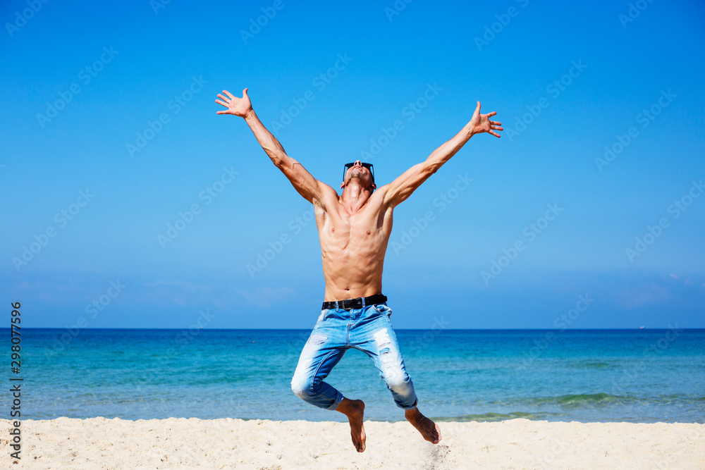 young muscular man resting and posing on the beach. Jump in the air young muscular man resting and posing on the beach. Jump in the air