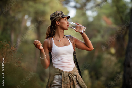 Young woman having water break while exploring the nature.
