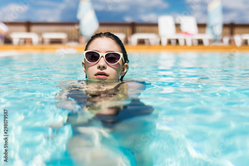 Young woman in sunglasses swim in the pool. Summer vocation.