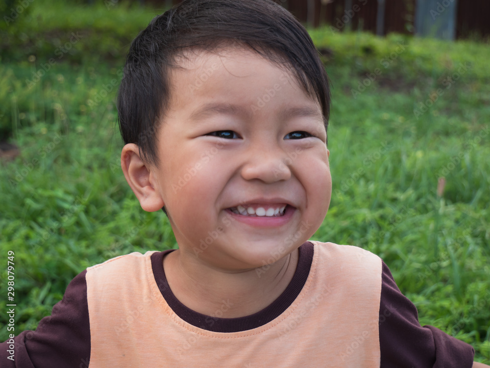 Asian child boy laughing with happy close up funny face outdoor with natural background. Family relax and freedom time in summer holiday. Young kid smile while playing outdoor. Asian child boy laughing with happy close up funny face outdoor with natural background. Family relax and freedom time in summer holiday. Young kid smile while playing outdoor.