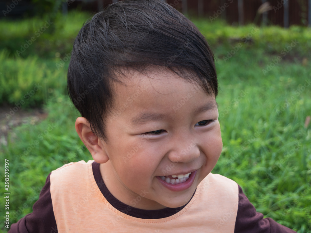 Asian child boy laughing with happy close up funny face outdoor with natural background. Family relax and freedom time in summer holiday. Young kid smile while playing outdoor. Asian child boy laughing with happy close up funny face outdoor with natural background. Family relax and freedom time in summer holiday. Young kid smile while playing outdoor.