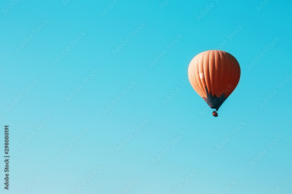 Fototapeta premium Orange balloon soars against the blue sky