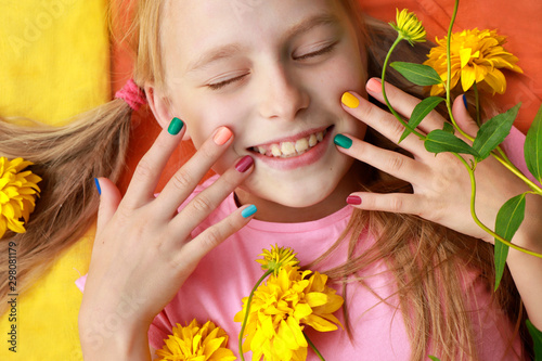 Bright and colorful children's manicure on the nails of girls with yellow flowers and good mood.