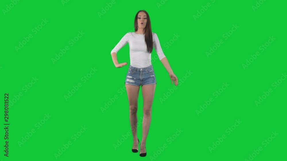 Young beautiful brunette woman waving and welcoming hello at camera. Full body isolated on green screen chroma key background Young beautiful brunette woman waving and welcoming hello at camera. Full body isolated on green screen chroma key background